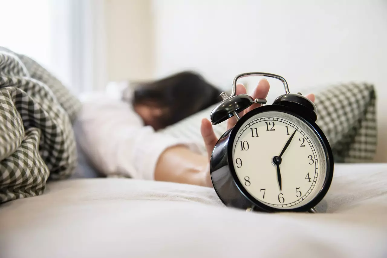 sleepy-woman-reaching-holding-alarm-clock-1